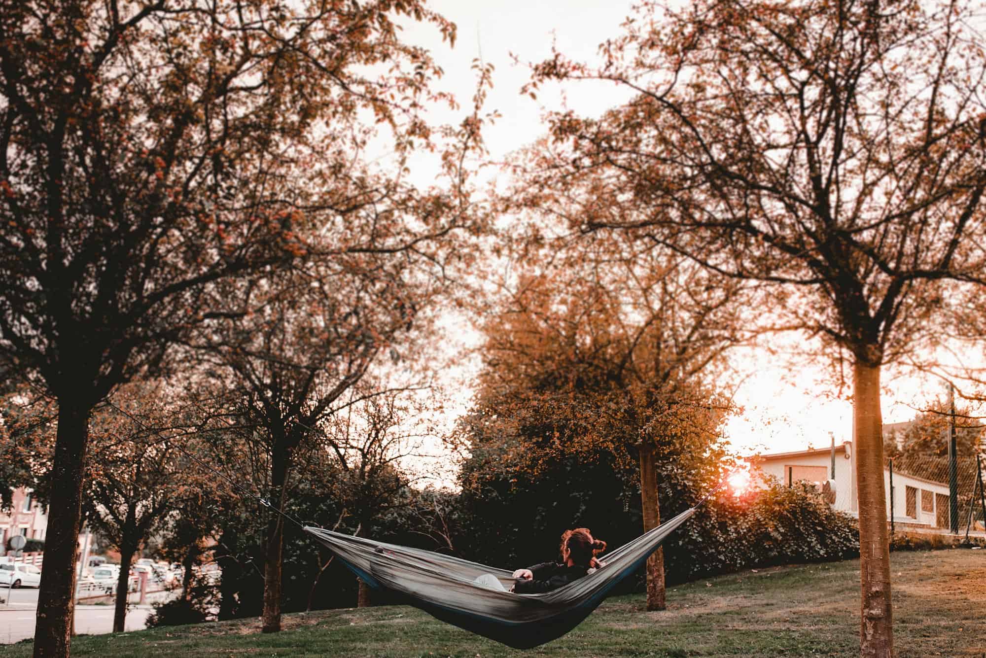 Woman lying in hammock between trees in yard